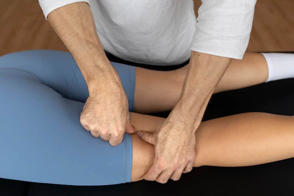 Fisioterapeuta trabajando la movilidad de la rodilla de un paciente durante una sesión de rehabilitación